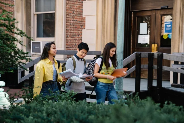 Students walking and talking outside a university building.